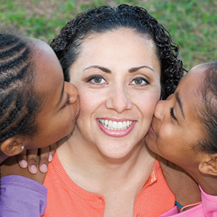 Photo of girls kissing the cheek of a woman. Link to Life Stage Gift Planner Ages 60-70 Situations.