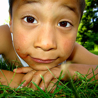 A kid laying in grass. Links to Gifts from Retirement Plans